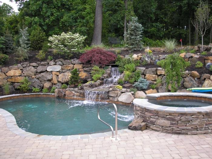 Trädgårdsdesign-med-stenar-pool-oval-bubbelpool-sluttning-plantering
