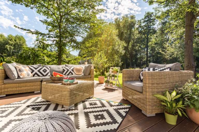 Trädgårdsmöbletrender för 2020 Lounge -grupp på terrassen med rottingmöbler och utomhusmatta