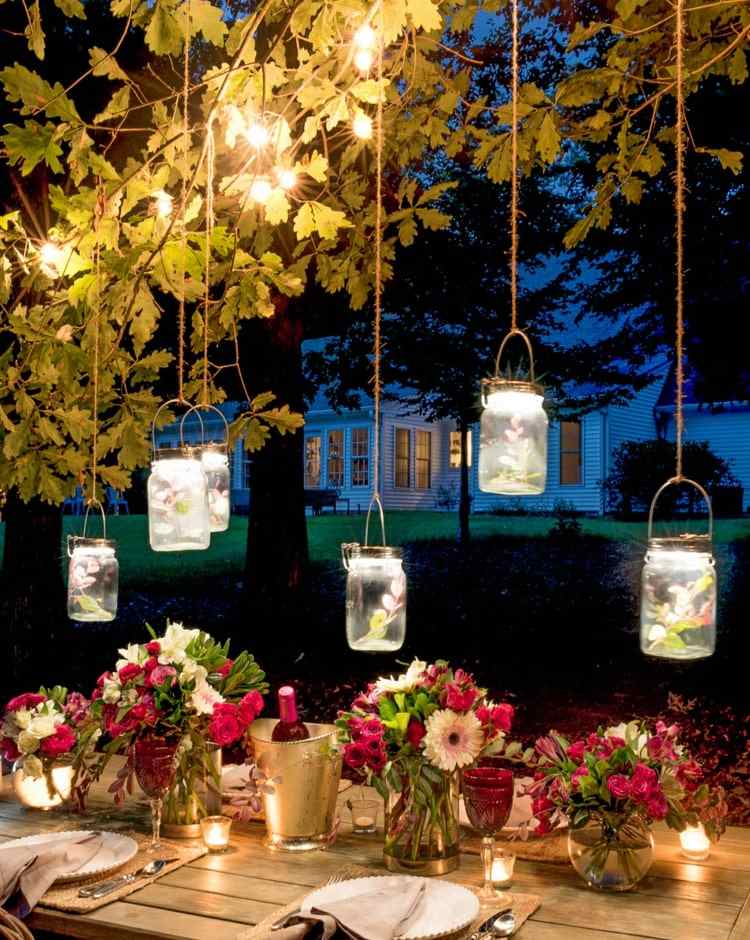 Masonburkar med sagoljus och blommor för romantiska festdekorationer i trädgården