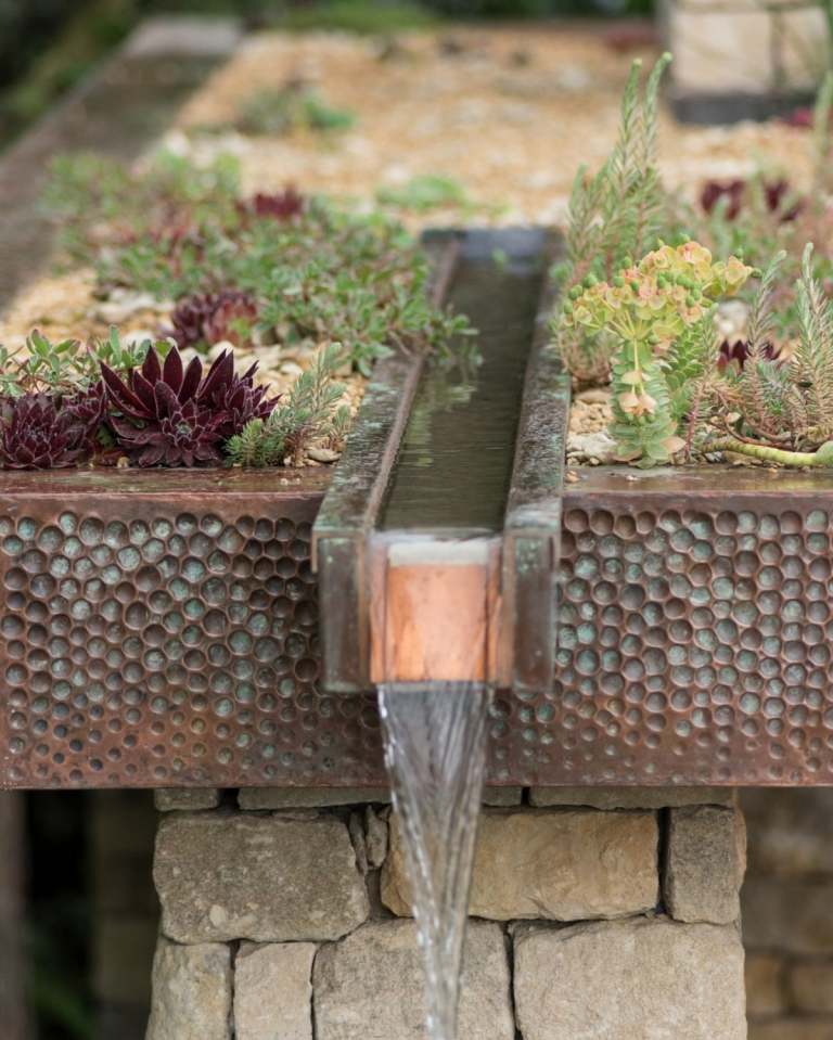 Vattenfunktion av koppar som en trädgårdstrend 2019 dekorerad med succulenter