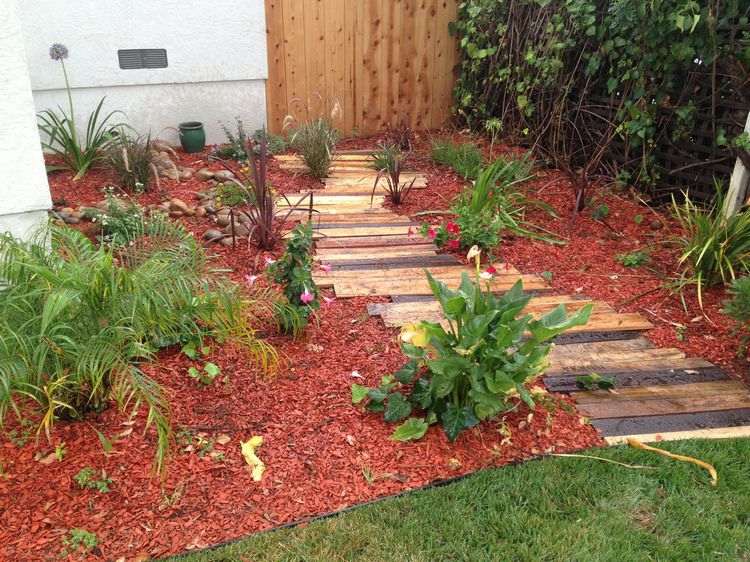 DIY trädgårdsstig gjord av återvunnet trä på röd mulch