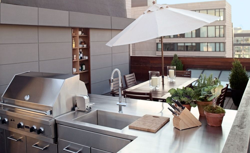 praktiskt kök av rostfritt stål på takterrassen med modern design och krukor och parasoll