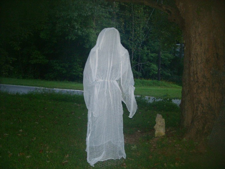 Flytande DIY Halloween -spöke med mantel bredvid ett träd
