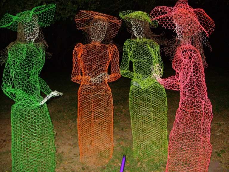 Färgglada spöken som Halloween -trädgårdsdekorationer i form av kvinnor med hattar