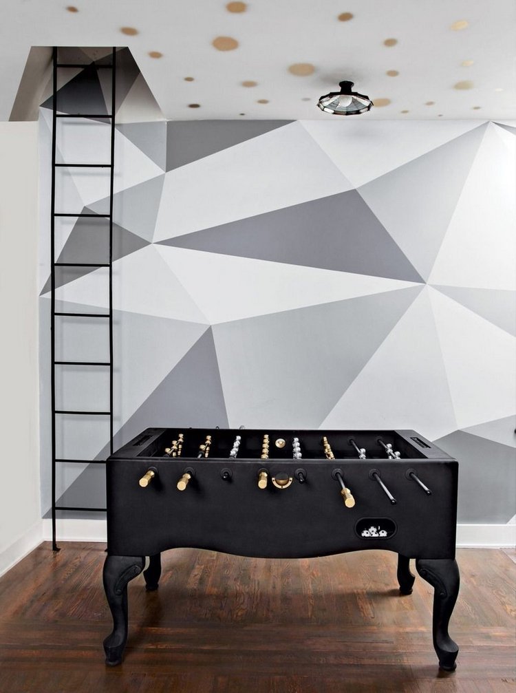 svart designer fotbollsbord i ett rum med geometriska väggmönster och stege