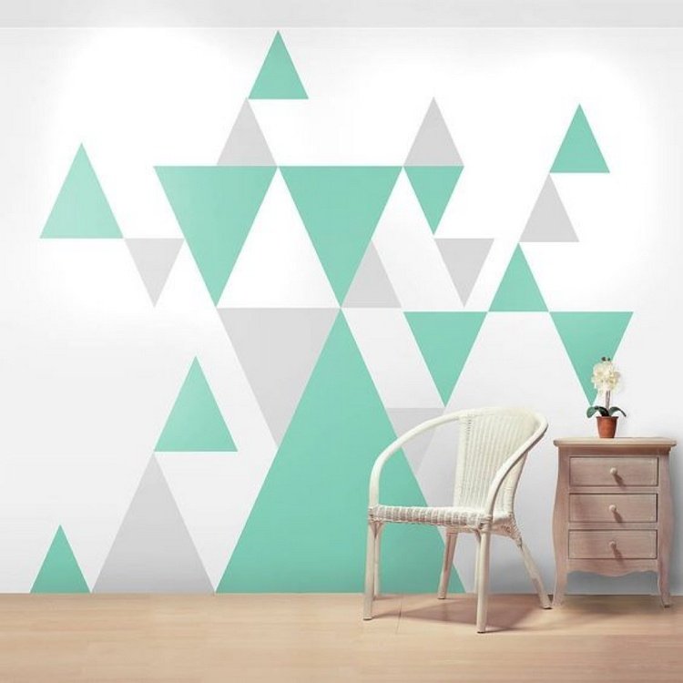 mintgröna trianglar som ett geometriskt väggmönster i ett vardagsrum med en byrå och en stol.jpg