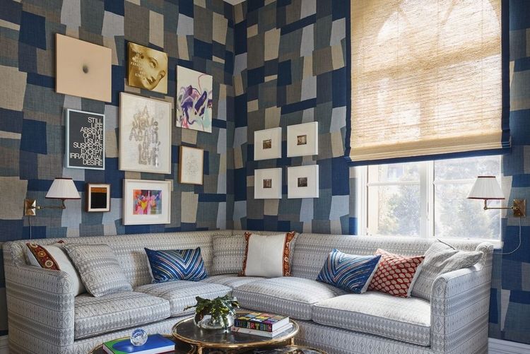 kubistiskt geometriskt väggmönster i blått som collage i vardagsrummet med hörnsoffa i grått