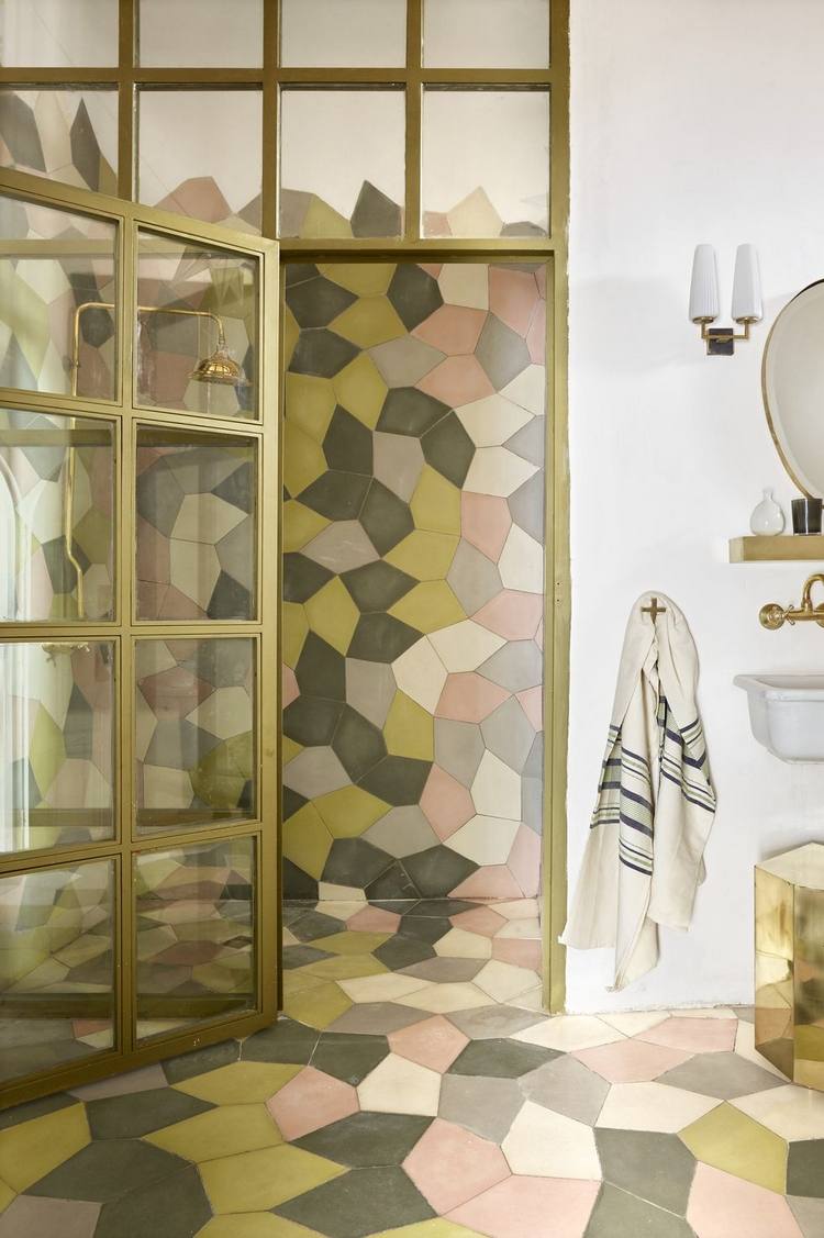 duschbakvägg med geometriska former och mönster i ljusrosa och jordnära färger med en gyllene dörrkarm