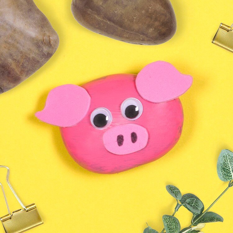 Nyårsafton grisar gör hantverk av flodstenar, målar idéer för gör-det-själv lyckliga charm