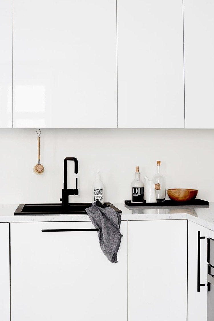 snyggt kök i svartvitt med handfat i granit rent med en trasa och borste