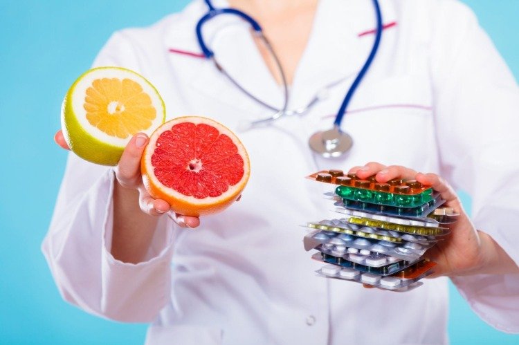 läkare håller citron med grapefrukt och medicinering i båda händerna