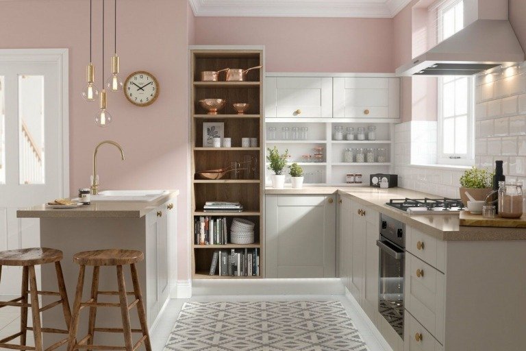 ljusgrå köksskåp och rosa väggfärg och bänkskiva i grädde av natursten och guldbeslag