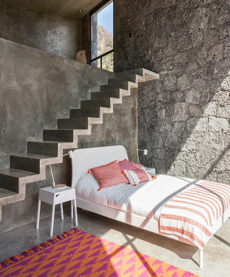 natursten vägg sovrum-orange-rosa-inredning-vit-säng-betong-golv-grå