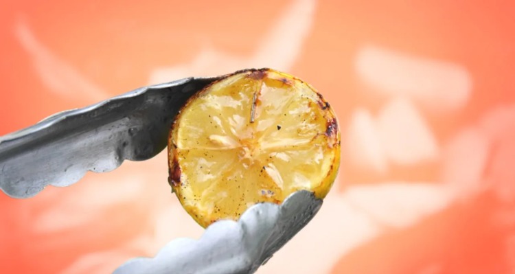 Håll grillad citron med en tång över brinnande kol