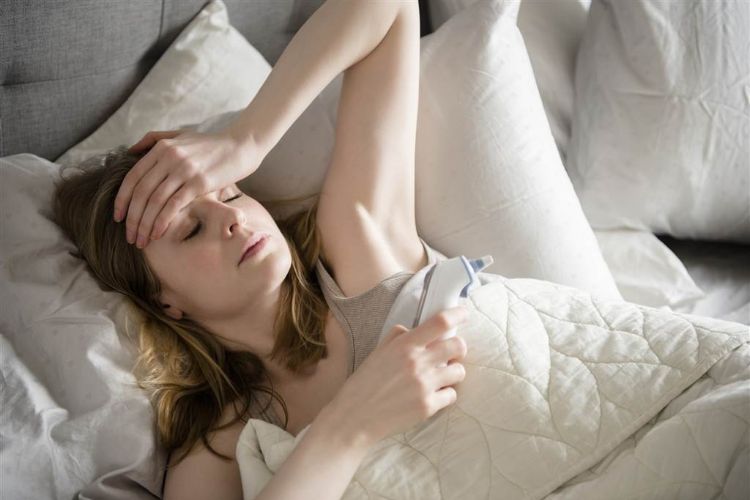 Kvinna som ligger i sängen med influensa eller förkylning och feber som blockerar rhinovirus