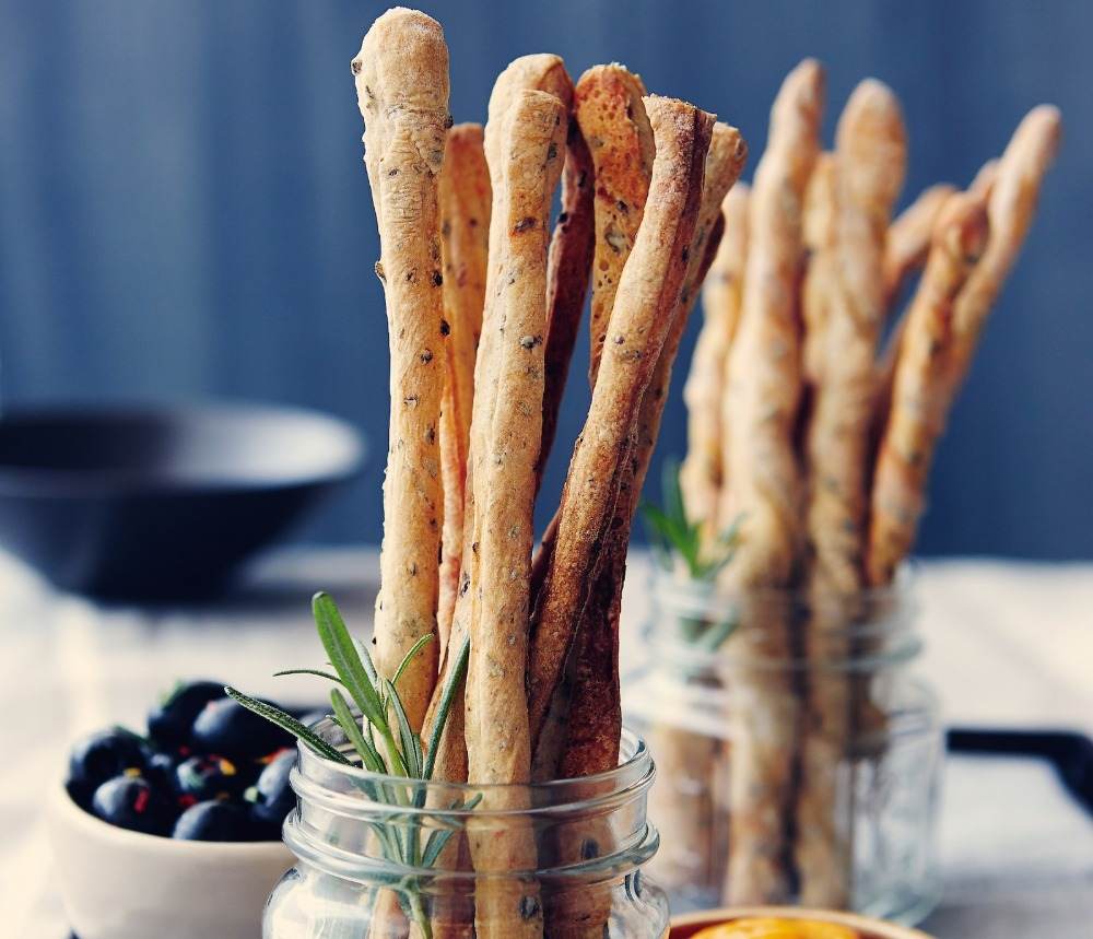 Brödpinnar i italiensk stil med oliver och rosmarin i glasbehållare