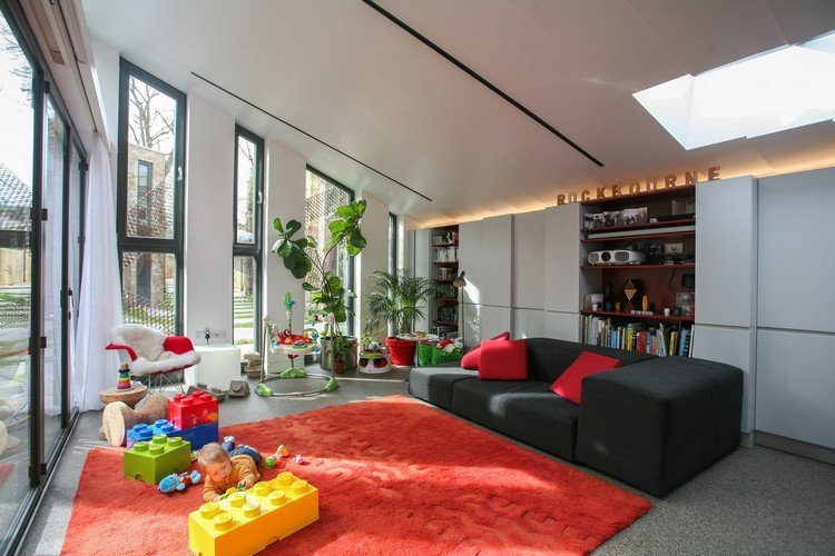 vardagsrum-naturligt-ljus-sluttande tak-stora-fönster-färgade-möbler