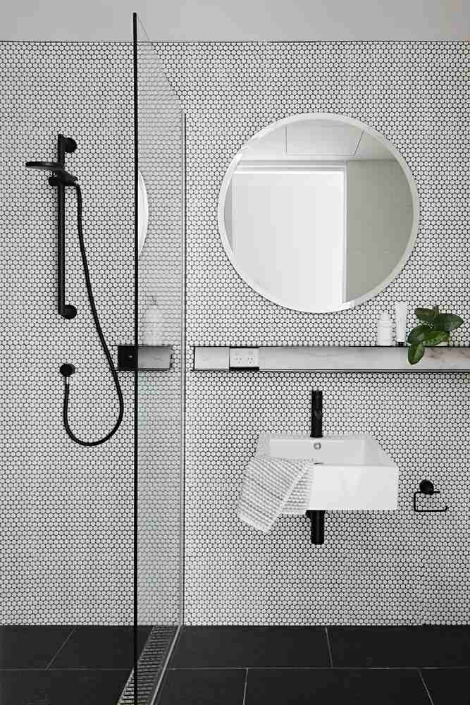 Badrum vita väggplattor bikakemönster svart duschkran