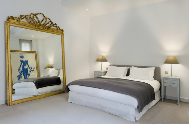 Stort sovrum inrett utan möbler med en enorm spegel och bild på väggen