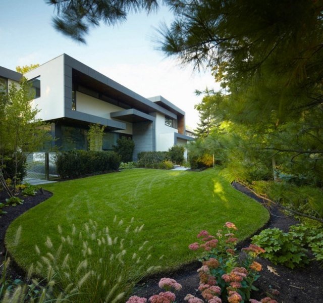 Modernt plant takhus med gräsmatta med rabatter