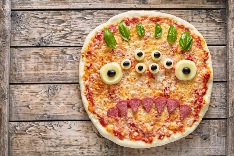 Gör halloweenpizza som ett monster med massor av ögon och tänder av salami