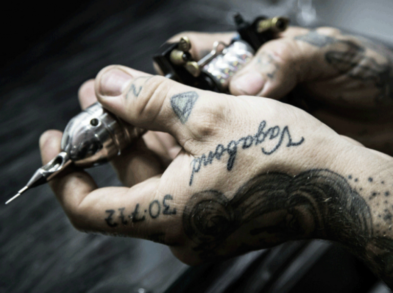 Tatueringsmaskin i händerna med meddelandetatueringar