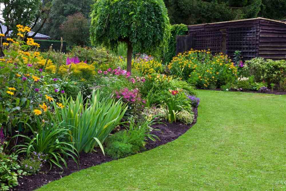 vackert utformad trädgård med en sluttning förvandlad till en blomsträdgård och gräsmatta