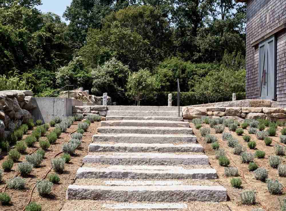 erosionsskydd genom stenläggning av lutningen, betong med trappor och terrasser med växter och halmtak