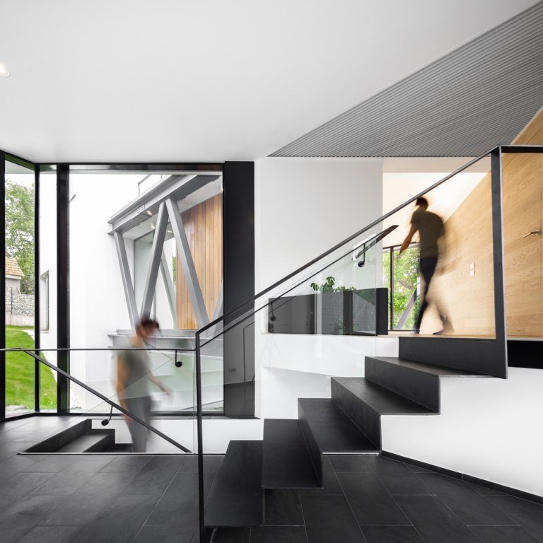 Modernt enfamiljshus med ett trapphus av skiffer och vita putsade väggar och glasräcken och fönster i golv