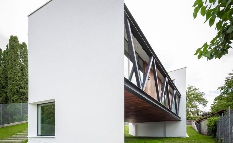 Hus på en sluttning med en putsad vit fasad med stora fönster och träelement