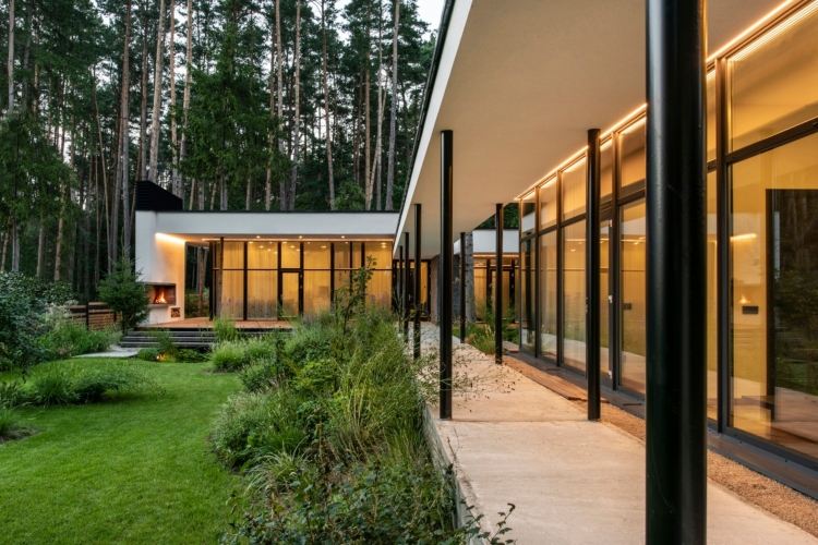hus med glasfront villa skog gräsmatta
