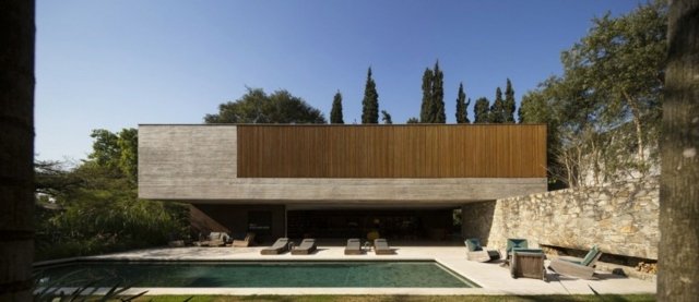 Modernt hus sten fasad trä persienner solstolar poolområdet