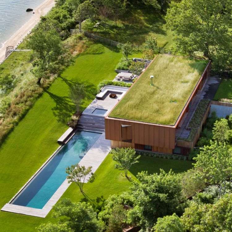 hus med träpanel design fågel utsikt tak greener pool natur gräsmatta kust havet