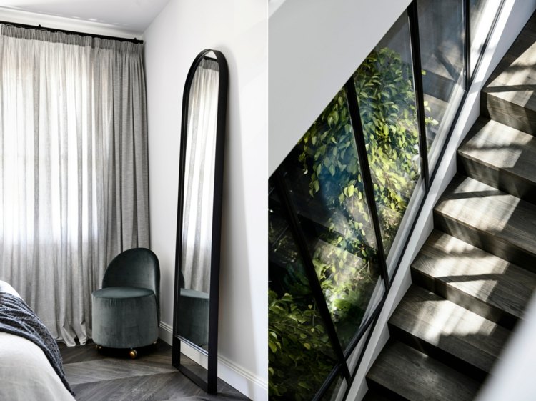Stående spegel med svart metallram i sovrummet och trappor av grått trä