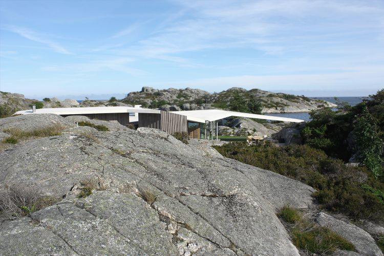 stor sten vulkan bakom området hus med sluttande tak himmel dagsljus grön plantering