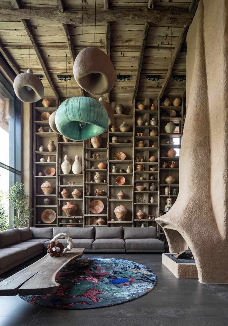 Rustikt vardagsrum med öppen spis och trähyllor fyllda med keramiska kärl och hängande lampor