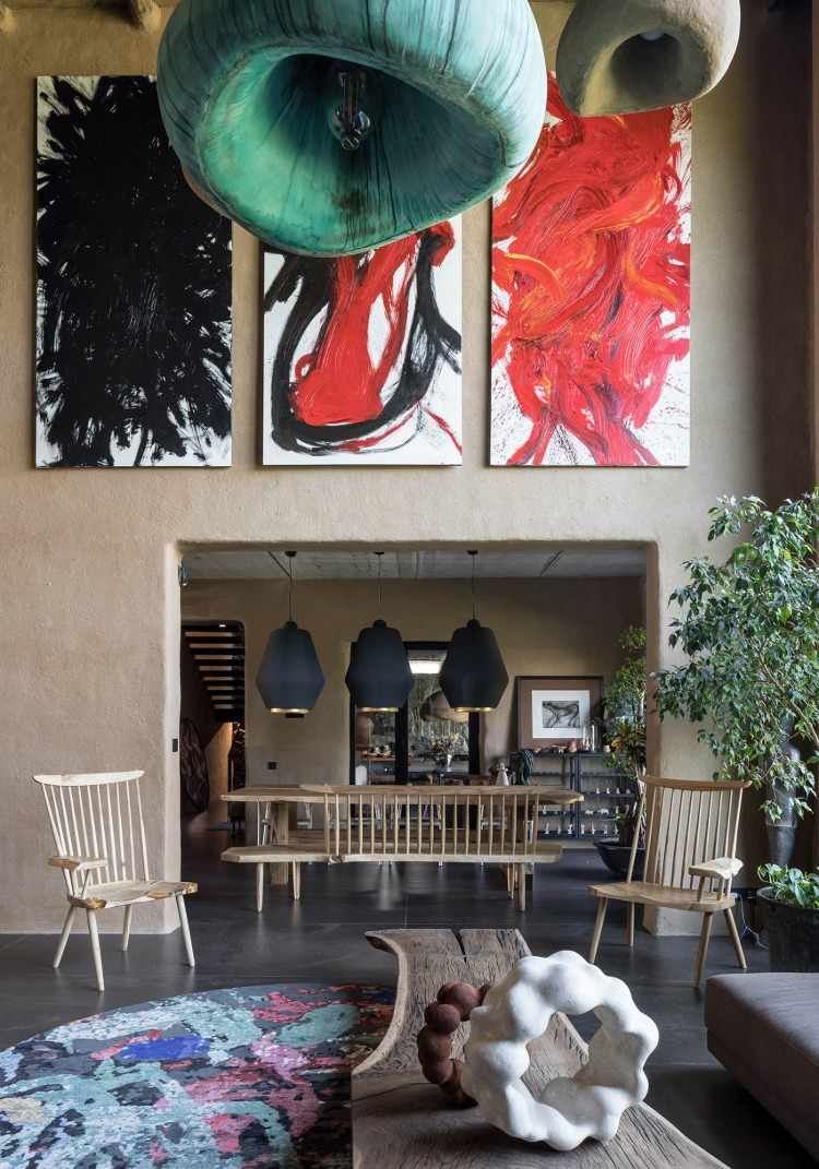 Målningar hänger över vardagsrum med konstnärliga element i hus med halmtak