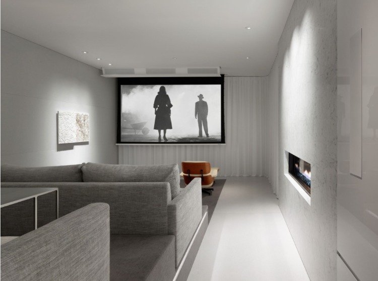 minimalistiskt biorum med inbyggd öppen spis och sittplatser i gråtoner