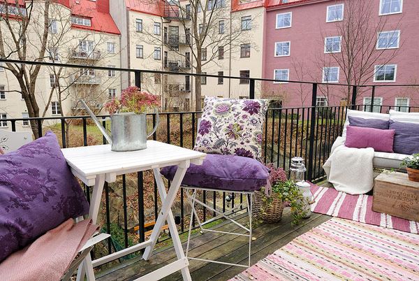 Balkong uppsatta soffbord stolar lila kuddar blommönster