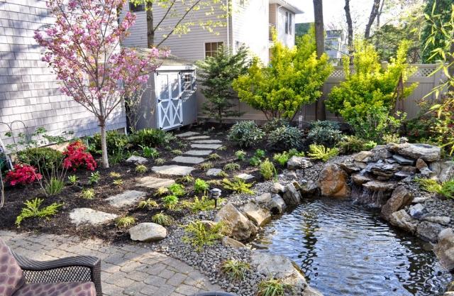 designträdgård med vatten små dammgränsstenar som lägger trädgårdsvägar