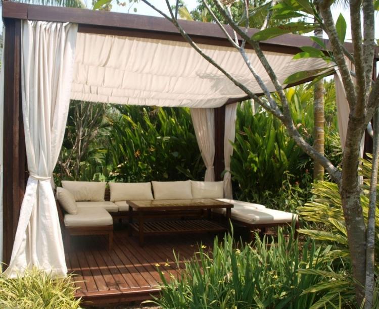 trä-pergola-gardiner-soffa-klädsel-kuddar-grädde-vit-foundation-växter-träd-exotiska