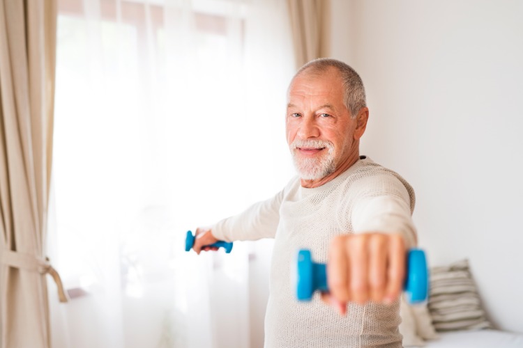 Äldre man senior med lätta vikter övningar hemma hemma träning män