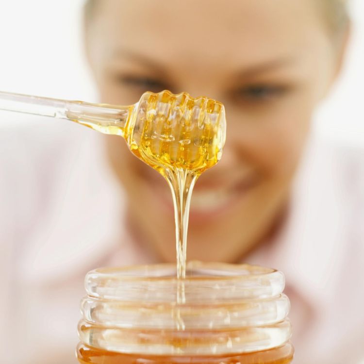 ta biodlarhonung ur burken med en flytande konsistens av en honungssked