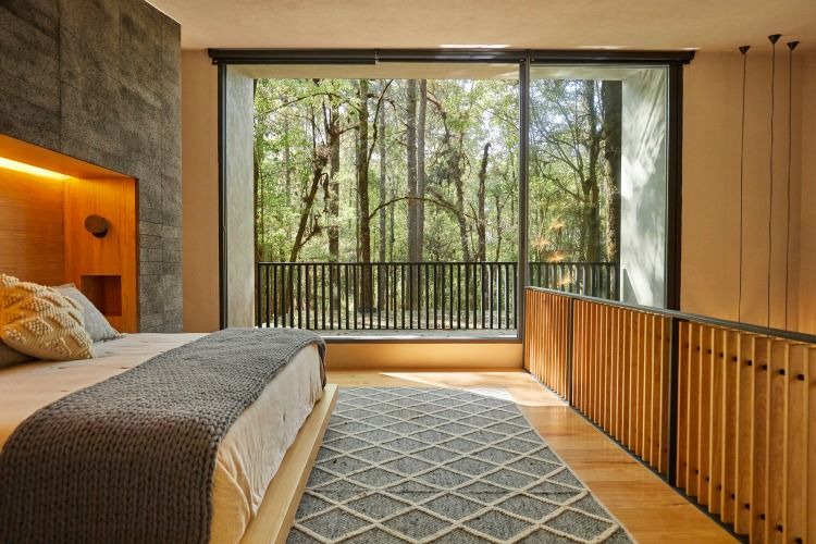 bekvämt snyggt sovrum med ett stort fönster med utsikt över skogen