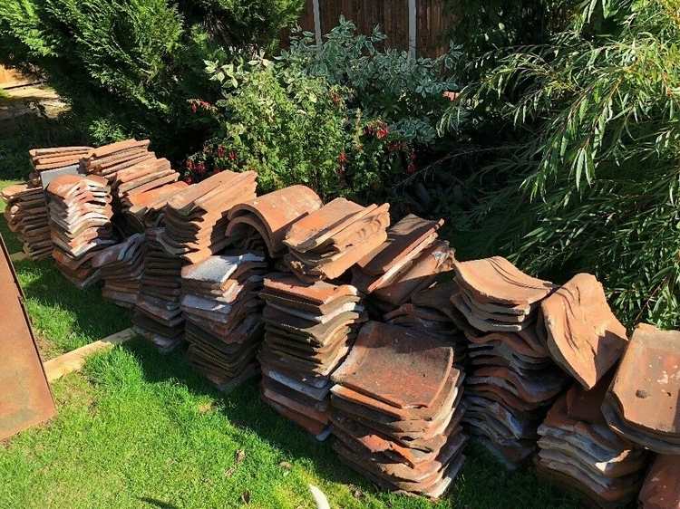 Staplade gamla takpannor i trädgården redo för återanvändning