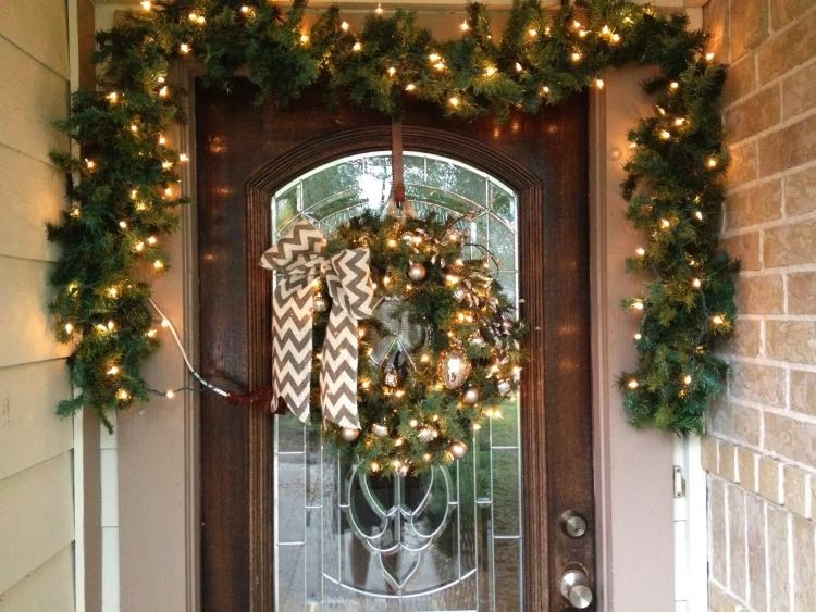 juldekoration-utanför-belyst-hus-dörr-dörr-krans-jul-bollar-gran grenar-glas-trä-tegel-vägg
