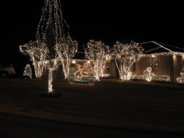 juldekoration-utanför-belyst-hus-vita-ljus-jultomten-träd-buskar-lampor