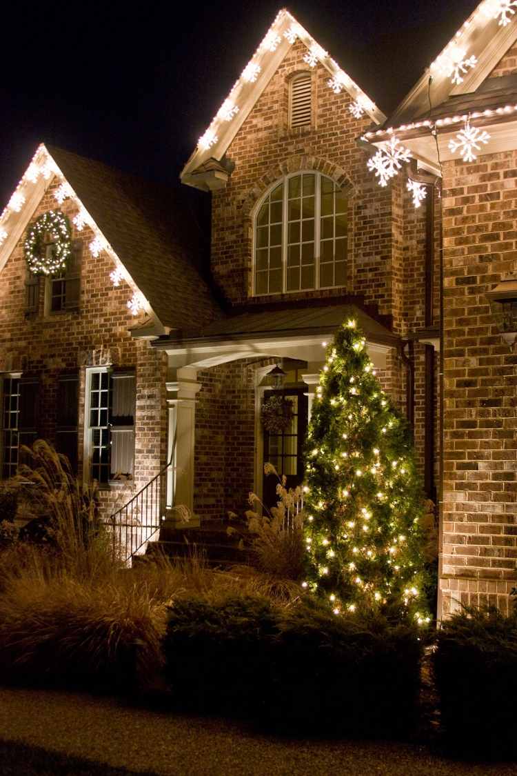 juldekoration-utanför-belyst-hus-vacker-utomhus-belysning-snöflingor-gran-träd-lampor