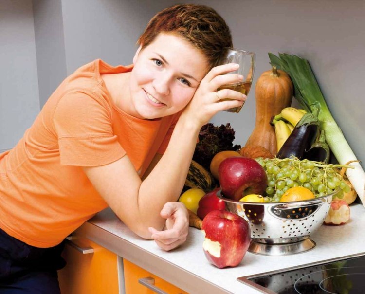immunsystem-stärka-frukt-grönsaker-sil-te-glas-kvinna-kök-bänkskiva-spishäll-bas-skåp-orange