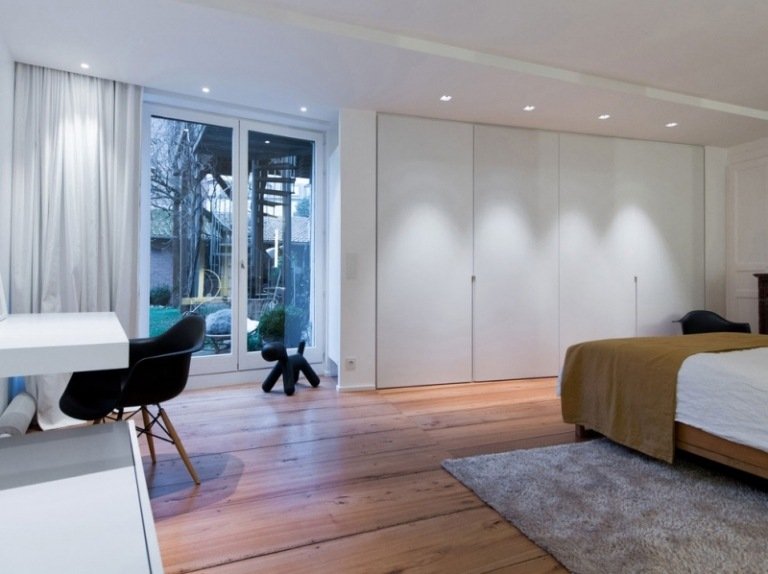 svart-vit-möbler-sovrum-golvbrädor-inbyggd garderob-gardiner-fläckar-säng-matta